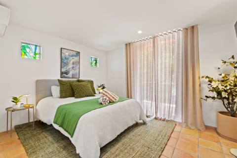 Ground-floor queen bedroom with green linen, terracotta floors and doors to the garden