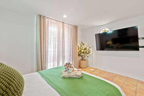 Ground-floor queen bedroom with wall-mounted television and terracotta floors