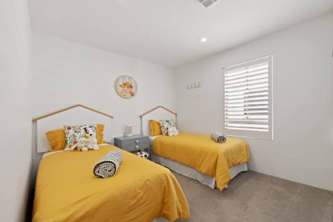 Twin bedroom with two single beds, mustard linen and house-shaped bedheads