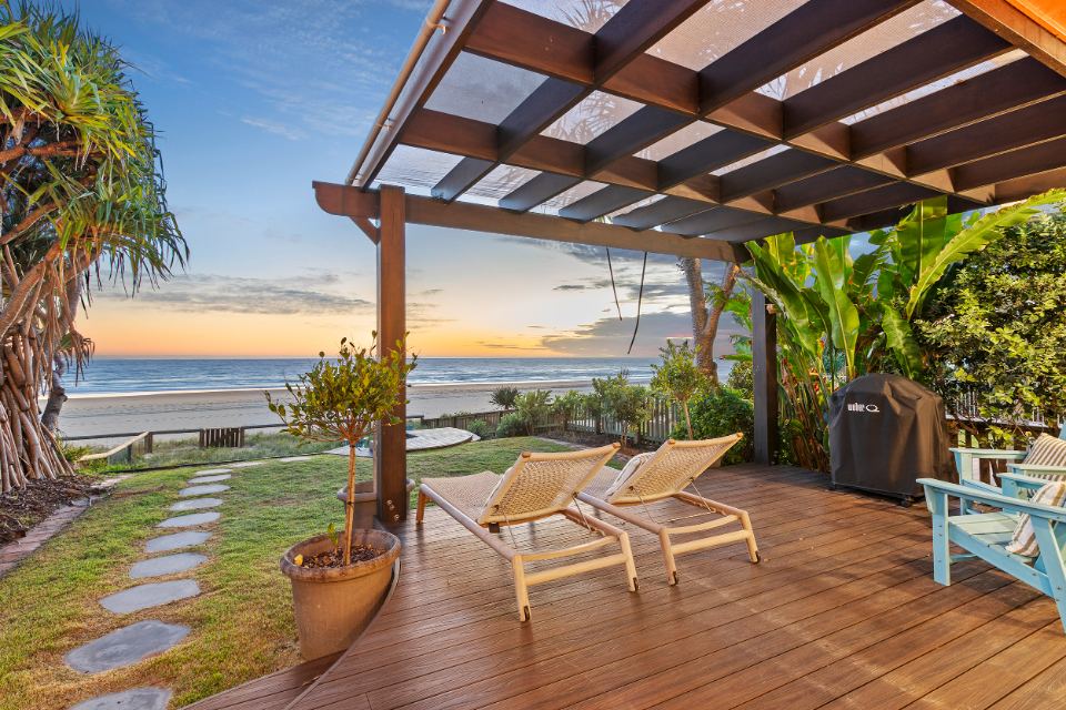 Timber deck and lawn running to the sand, with the ocean beyond