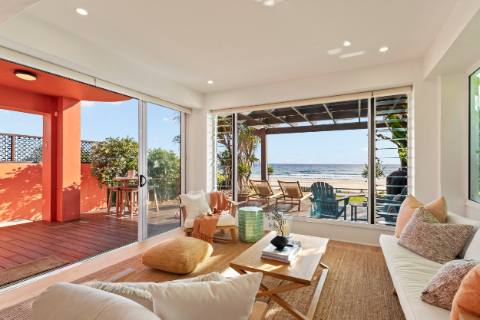 Open-plan living room opening onto the terracotta beachfront terrace and ocean
